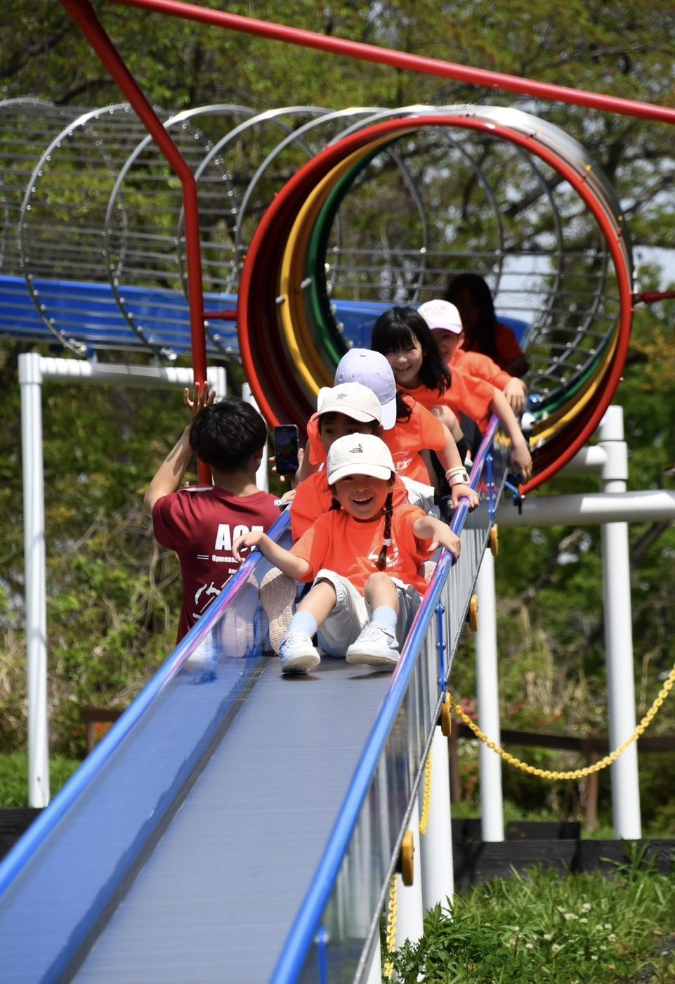 ローラーすべり台を笑顔ですべる子どもたち