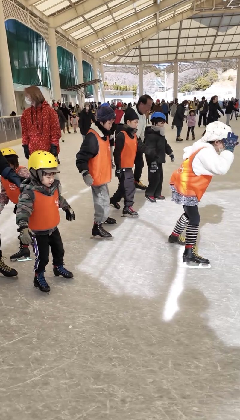 オレンジのビブスで列になって滑る子どもたち