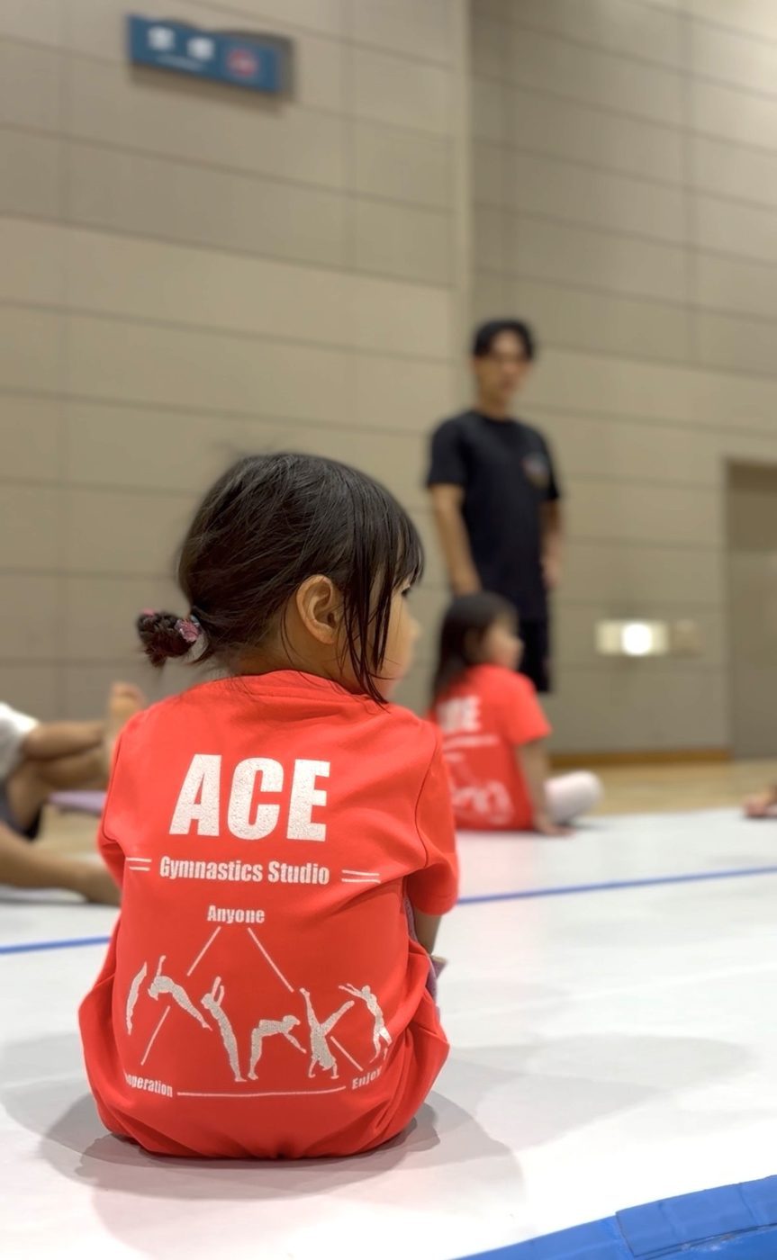 「Anyone・Cooperation・Enjoy」がプリントされたACEのTシャツを着た子ども
