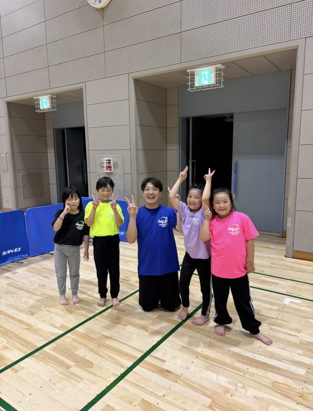 先生と笑顔でピースする子どもたち