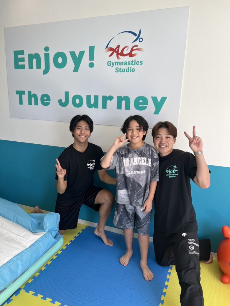 Enjoy the Journeyの前で笑顔の子どもと先生