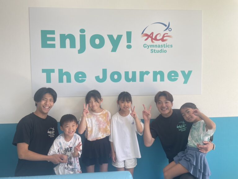 Enjoy the Journeyの前で笑顔の子どもたちと先生